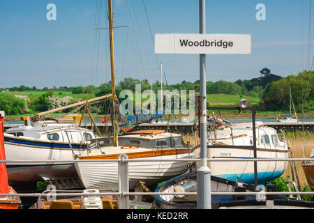 Woodbridge Suffolk UK, vue sur la plate-forme de la gare ferroviaire signe devant les bateaux à voile à côté de la rivière Deben à Woodbridge, Suffolk, Royaume-Uni. Banque D'Images