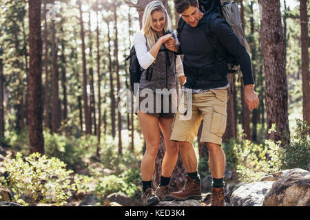 L'homme et la femme les randonneurs randonnée un sentier rocheux en forêt. Couple randonneur tenir la main et marcher avec précaution sur des rochers dans la forêt. Banque D'Images