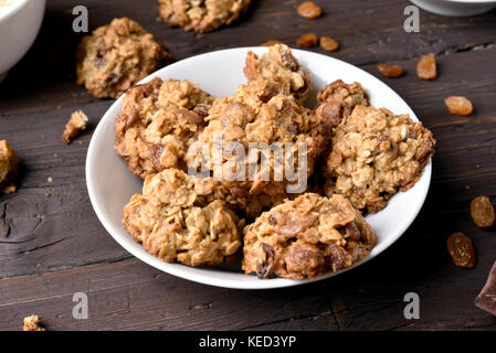 Sains savoureux biscuits aux pépites de chocolat et raisins dans la plaque sur une table en bois Banque D'Images