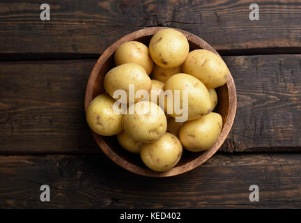 Les pommes de terre crues dans un bol sur table en bois avec copie espace, vue du dessus Banque D'Images