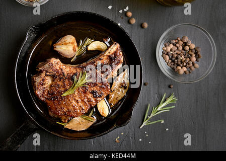 Escalope de porc dans la poêle sur fond sombre, vue du dessus Banque D'Images