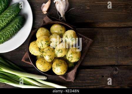 Des pommes de terre bouillies avec de l'aneth dans un bol sur fond de bois avec copie espace, vue du dessus Banque D'Images