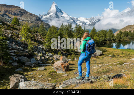 Randonneur se dresse sur les rochers et se penche sur la distance, derrière le grindijsee couverte de neige et Cervin, Valais, Suisse Banque D'Images