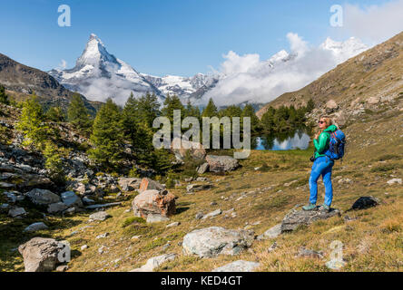 Randonneur se dresse sur les rochers et se penche sur la distance, derrière le grindijsee couverte de neige et Cervin, Valais, Suisse Banque D'Images