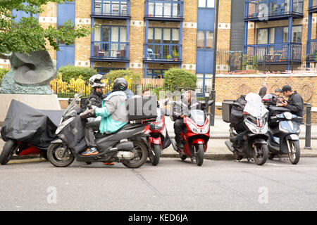 Groupe de cavaliers livraison y compris une Deliveroo rider ayant une pause en dehors du marché de Spitalfields à Londres, Angleterre Banque D'Images