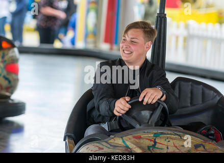 Jeune homme souriant alors qu'un trajet en voiture dodgem lors d'une fête foraine. Banque D'Images