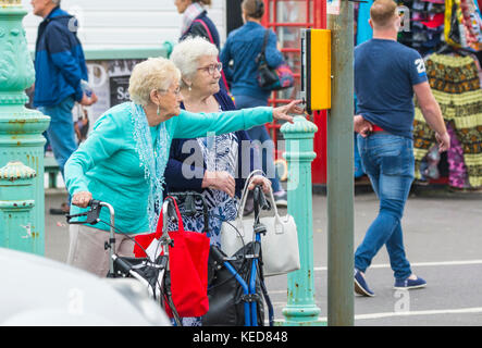 Femme âgée en appuyant sur le bouton à la Pelican crossing pour traverser la route à Brighton, East Sussex, Angleterre, Royaume-Uni. Banque D'Images