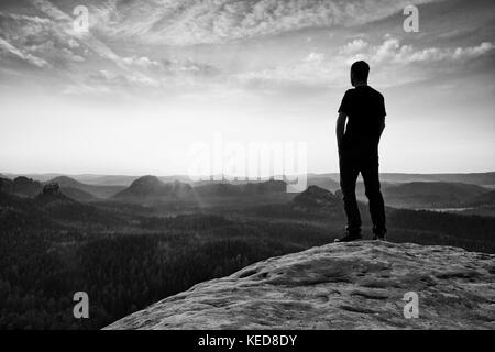 Grand randonneur en montagne. Penser l'homme dans la nature dans l'aube. l'effet du vignettage.photo en noir et blanc Banque D'Images