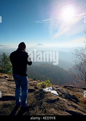 Homme de grande taille est de prendre en photo l'appareil photo miroir sur le cou. snowy piton rocheux de montagne. photographe professionnel prend des photos avec l'appareil photo sur le pic de miroir Banque D'Images