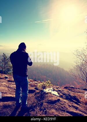 Homme de grande taille est de prendre en photo l'appareil photo miroir sur le cou. snowy piton rocheux de montagne. photographe professionnel prend des photos avec l'appareil photo sur le pic de miroir Banque D'Images