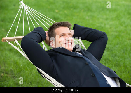 Happy young woman lying in hammock at park Banque D'Images