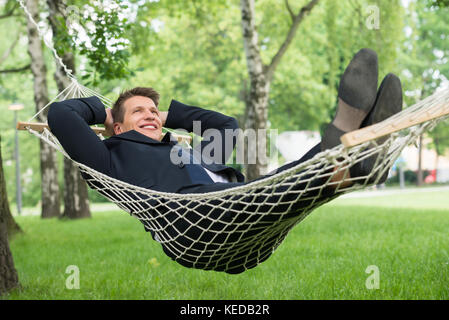 Happy Young Woman Lying in Hammock At Park Banque D'Images