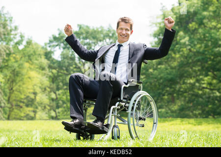 Heureux les jeunes personnes handicapées en fauteuil roulant sur l'homme avec les bras levés dans la région de Park Banque D'Images