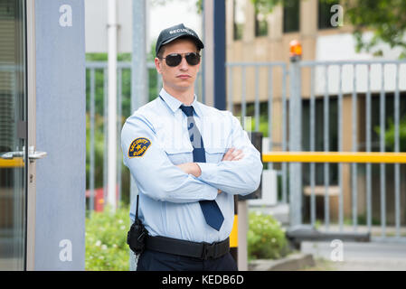 Certain Jeune Homme bras croisé permanent Agent de sécurité Banque D'Images