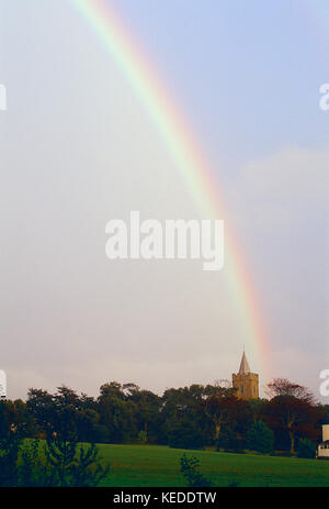 Guernesey. Arc-en-ciel sur la prairie et l'église Saint-Sauveur, Banque D'Images