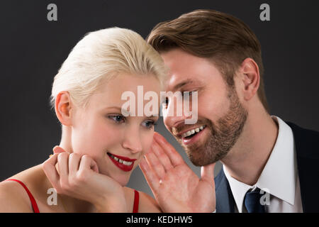 Portrait de jeune homme chuchoter dans l'oreille d'une femme dans un restaurant. Banque D'Images