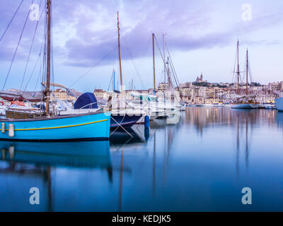 Yachts se reflétant dans les vieux vieux port de Marseille sous notre dame de Paris, France, par nuit. Banque D'Images