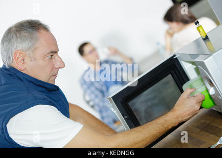 Man putting lunch box en four à micro-ondes pour cuire Banque D'Images