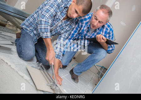 Pose de carreaux en céramique l'homme dans un nouveau bâtiment Banque D'Images