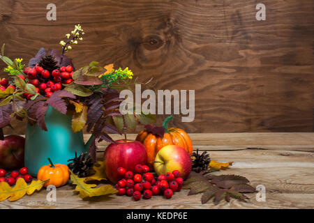 Centre de table d'automne avec des baies de Rowan et de feuilles dans vase turquoise, citrouilles, pommes, cônes, copy space Banque D'Images