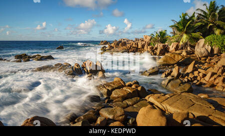 Vagues se briser contre les roches de granit doré en face d'une jungle sauvage rugueux. - l'autre côté du paradis sur les seychelles. Banque D'Images