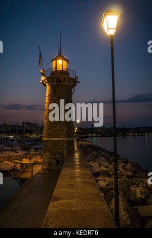 Un phare à la lumière des lanternes dans le port sur le lac de garde dans la nuit Banque D'Images