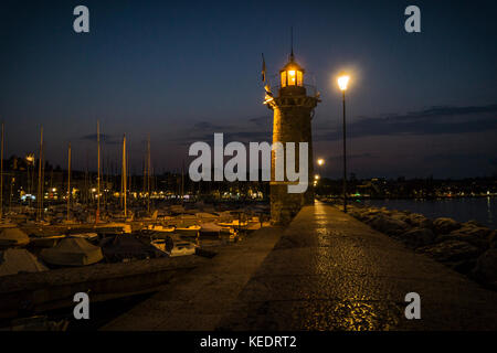 Un phare à la lumière des lanternes dans le port sur le lac de garde dans la nuit Banque D'Images