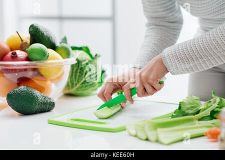 La préparation des aliments femme dans sa cuisine, elle est couper céleri frais sur une planche à découper, un couteau Banque D'Images