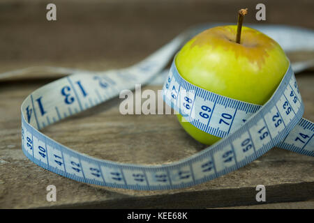 Close-up de pomme verte avec ruban à mesurer sur table en bois Banque D'Images