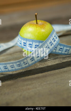 Close-up de pomme verte avec ruban à mesurer sur table en bois Banque D'Images