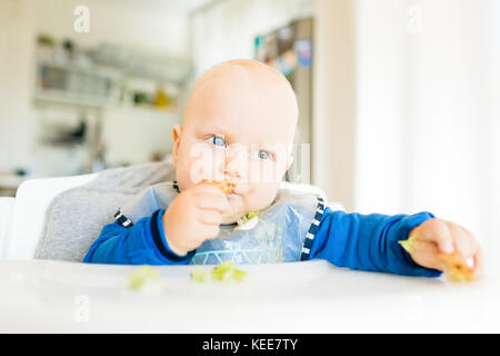 Baby Boy eating bread et concombre avec méthode, BLW led bébé sevrage. Seriosu kid végétarien au dîner. Manger de l'enfant lui-même, auto-alimentent. Banque D'Images