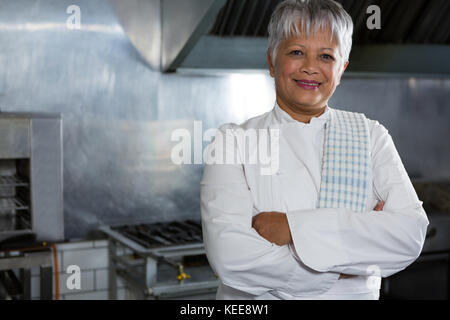 Portrait of smiling female chef avec mains croisées dans la cuisine Banque D'Images