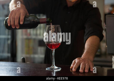 La mi-section de waiter pouring vin dans le verre Banque D'Images