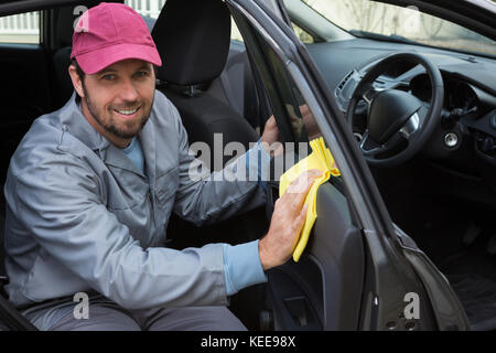 Portrait of smiling male auto service de nettoyage le personnel porte de voiture Banque D'Images