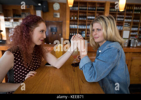 Happy female friends Arm wrestling en bar Banque D'Images