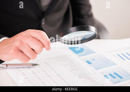 Businessman reading documents avec loupe concept pour l'analyse d'un finances Banque D'Images