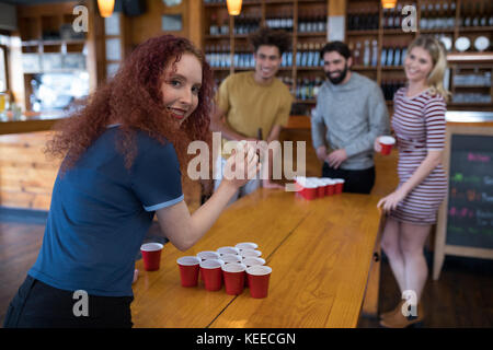 Portrait of smiling woman playing beer pong jeu avec vos amis dans le bar Banque D'Images