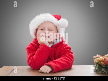 Digital composite de garçon contre l'arrière-plan gris avec noël santa hat Banque D'Images