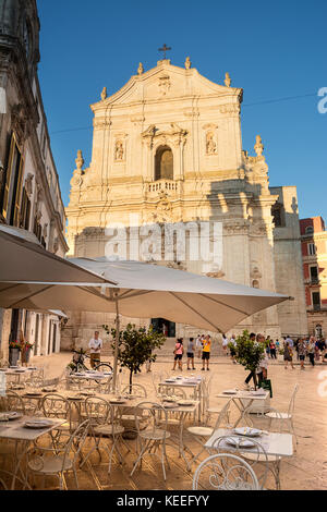 Martina Franca, Italie - 14 août 2017 : tables à café et les touristes, en face de la Basilique Saint Martin au coucher du soleil Banque D'Images