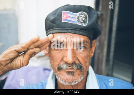 Homme cubain patriotique salue comme un soldat en portant un chapeau avec un drapeau cubain et l'image de la Che Guevara. Banque D'Images