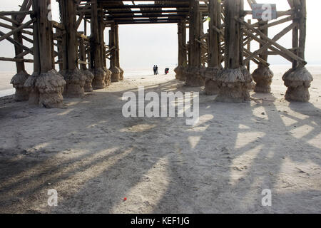 Sharafkhaneh, Sharafkhaneh, Iran. 9 octobre 2009. Les gens du coin sont vus marcher à travers le lac sous un homme fait de la construction.Sharafkhaneh est situé sur le lac Urmia, un lac de sel avec plus de 5000 kilomètres carrés de diamètre et plus de 100 petites îles rocheuses. C'est une réserve de biosphère de l'UNESCO qui abrite plus de 200 espèces d'oiseaux et beaucoup d'autres espèces de reptiles, d'amphibiens et de mammifères, dont le cerf jaune iranien. Le lac s'est rétréci depuis longtemps, et la construction d'un barrage et les récentes sécheresses ont considérablement réduit sa quantité d'eau. L'évaporation de l'eau h Banque D'Images