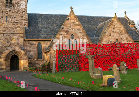 Aberlady, East Lothian, Ecosse, Royaume-Uni. 20 Oct, 2017. Aberlady l'Église et de l'église décorée de coquelicots rouges en vinyle noire organisée par Aberlady Craft groupe, en préparation pour le Jour du souvenir et à recueillir des fonds pour l'Écosse, de pavot sur une journée ensoleillée d'automne avec ciel bleu. L'extérieur de l'église est ornée d'un énorme crochet Nous nous souviendrons bannière de pavot. Coquelicots en bonneterie est coincé dans l'herbe des accotements le cimetière Banque D'Images