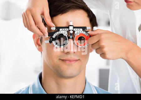 Close-up d'un optométriste contrôle Male Patient Vision avec le cadre à l'essai clinique Banque D'Images