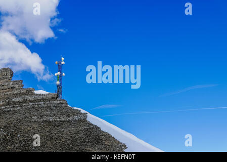 Tour de communication dans les montagnes alpines élevées contre le fond de ciel bleu clair Banque D'Images