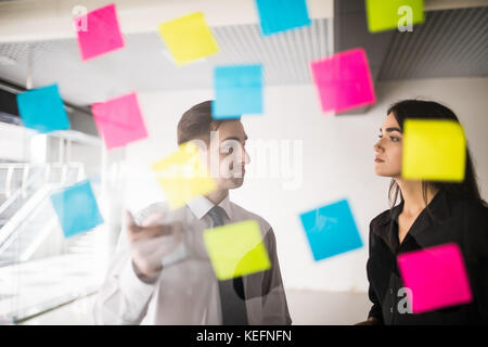 Autocollants colorés sur la façade de verre aident les femmes designer et son associé dans le travail Banque D'Images