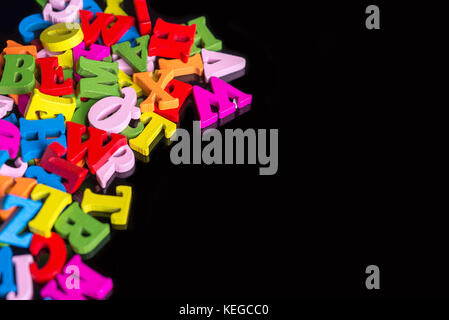 Beaucoup de lettres de couleur sur fond noir en plastique. Banque D'Images