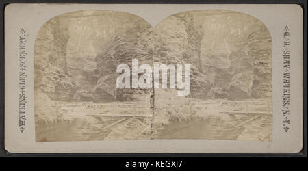 Cette image représente le célèbre Watkins Glen, mettant en valeur son paysage unique, ses cascades et sa beauté naturelle, capturée par le photographe G.B. Shay. Watkins Glen est connu pour ses gorges spectaculaires et son environnement luxuriant. Banque D'Images