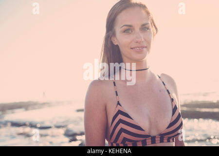 Femme caucasienne souriante portant le bikini sur la plage Banque D'Images