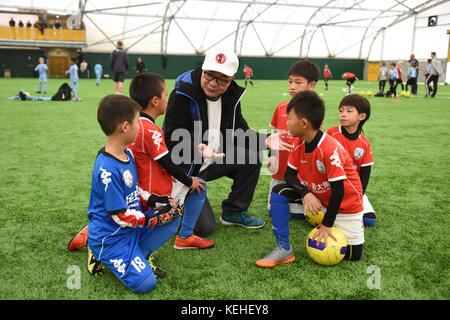 Commentateur de football chinois Dong Lu 'coaching' sous les garçons Football Chine 9 5 football équipe sur leur tournée au Royaume-Uni Banque D'Images