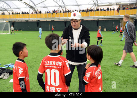 Commentateur de football chinois Dong Lu 'coaching' sous les garçons Football Chine 9 5 football équipe sur leur tournée au Royaume-Uni Banque D'Images